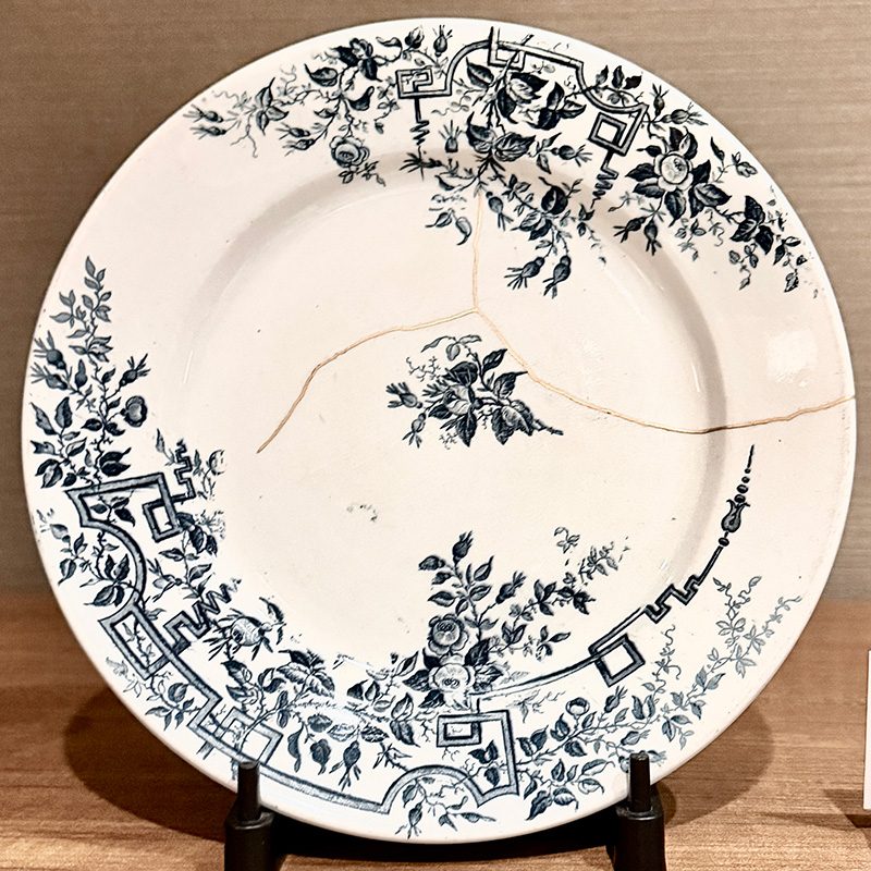 A white and blue floral porcelain plate with fine cracks repaired in gold, in the kintsugi style